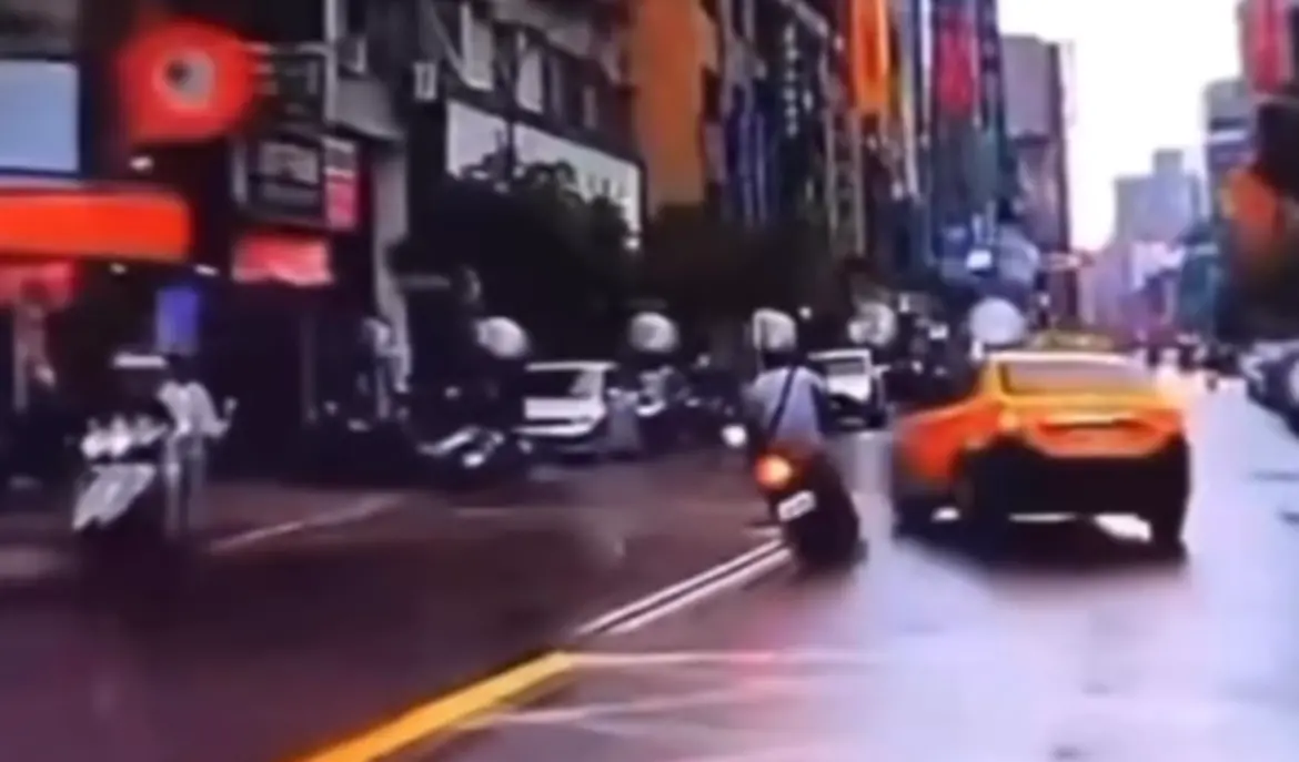 ▲ 事發於三重正義南路，一輛計程車突然左轉，一台直行機車當場撞上，駕駛被卡在車底，行車紀錄器畫面曝光。（圖／翻攝畫面）