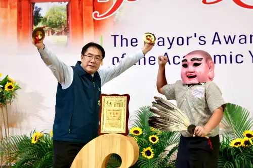 ▲學生扮成大頭佛與黃偉哲合影敲銅鈸。(圖／南市府提供)