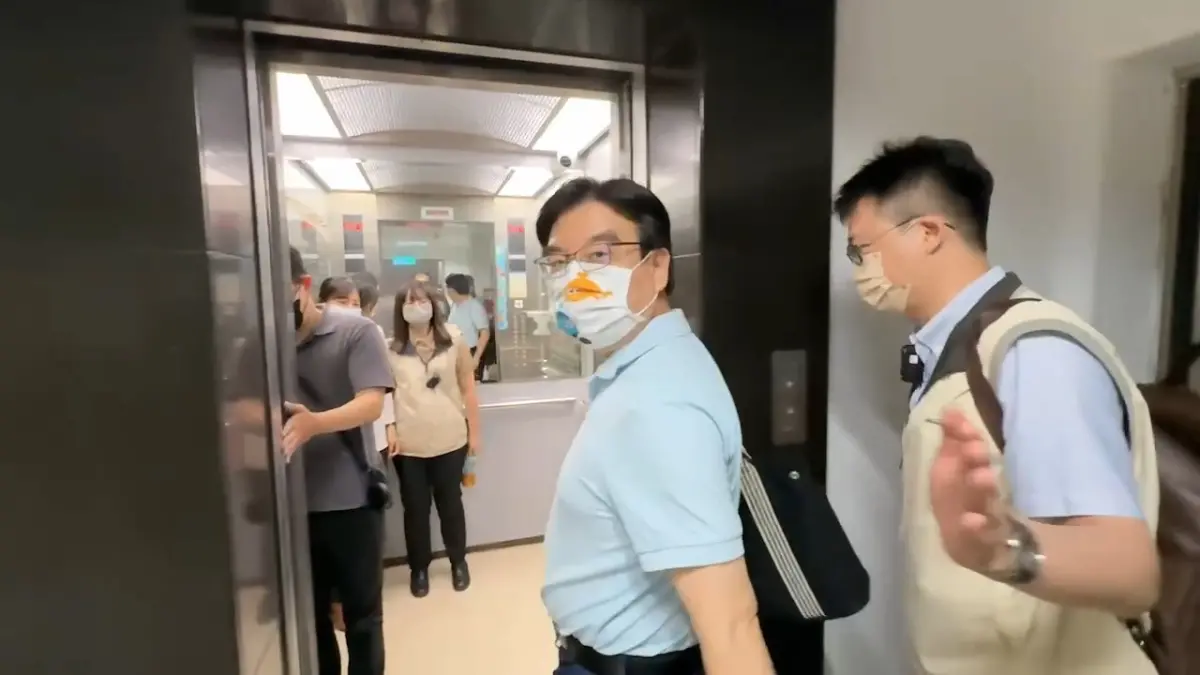 ▲台南市政府研考會主委蒙志成（淡藍上衣男）遭檢舉公務車私用，調查官上午搜索辦公室後將他帶走。（圖／翻攝畫面）