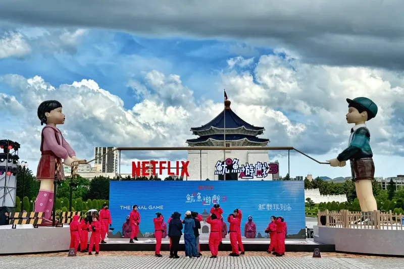 ▲Netflix為了宣傳《魷魚遊戲3》規劃多個城市的快閃活動，《魷魚遊戲3》台北場則是將7公尺高的「英熙娃娃」與玩伴「哲秀」一同在中正紀念堂現身，還打造「巨型跳繩遊戲裝置」，記者在開幕日前夕直擊現場，已看到不少民眾不畏高溫搶先目睹。（圖／記者葉盛耀攝）