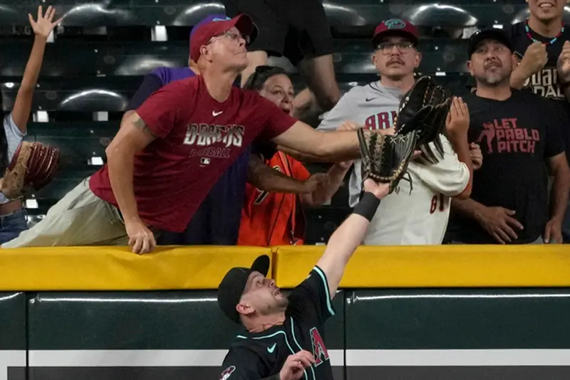 ▲響尾蛇主場惡名昭彰的「撈球哥」（紅衣者），昨日又刻意企圖干擾守備，遭球團驅逐出場，事後他接受外媒訪問，炫耀地表示在豐富的「撈球」歷史中，僅被驅逐出場過2次，企圖合理化昨戰的行徑。（圖／美聯社／達志影像）