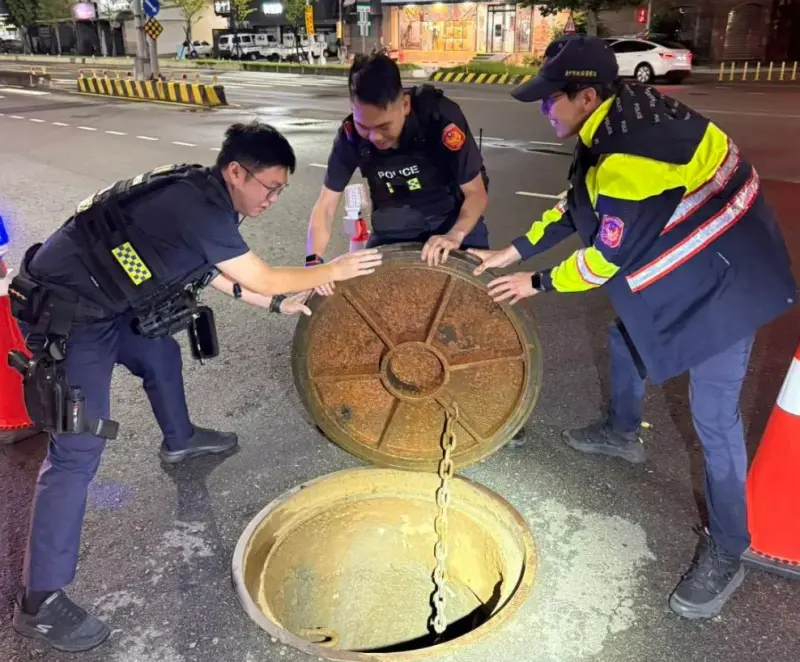 ▲台中市西屯區昨晚下起大雨，市政路重達百斤人孔蓋也因水壓被掀起離開孔位，3名警員合力將其搬回原處。（圖／警方提供）