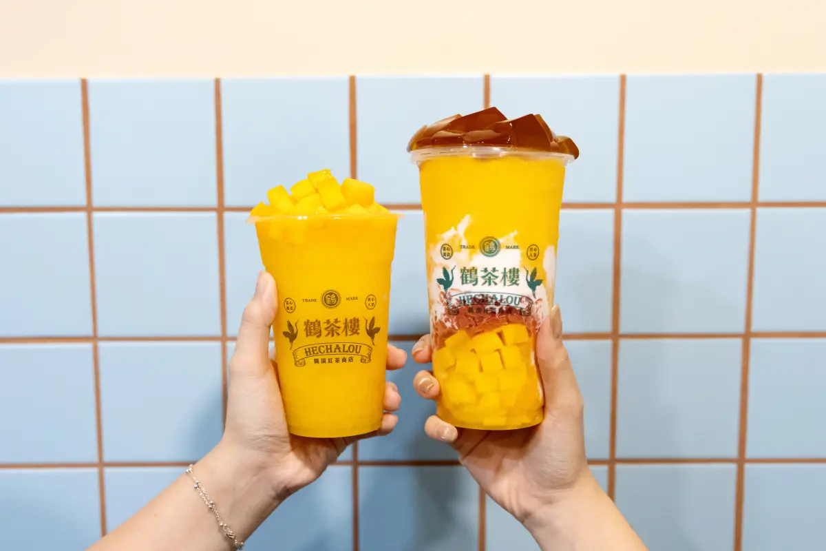 ▲周間「買一送一芒果手搖飲料」消暑優惠一次看！迷客夏49元加購；鶴茶樓買一送一、新品「愛文芒果冰沙、楊枝甘露」半價多一杯；萬波聯名小天使Mark Gonzales買芒果系列送10元折價券。（圖／鶴茶樓提供）