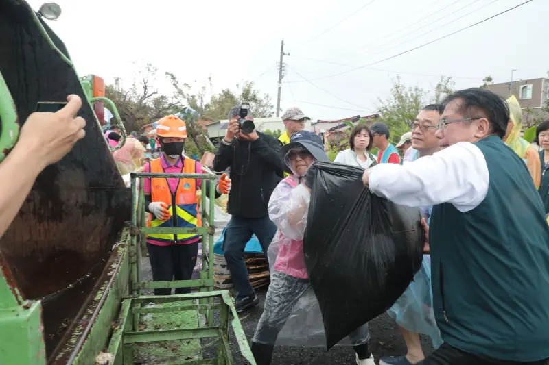▲台南市長黃偉哲今天前往受災嚴重的將軍區北嘉社區，訪視期間恰逢垃圾車到場清運，黃偉哲也協助搬運廢棄物，展現與市民同心、共同清理家園的決心。（圖／南市府提供） 