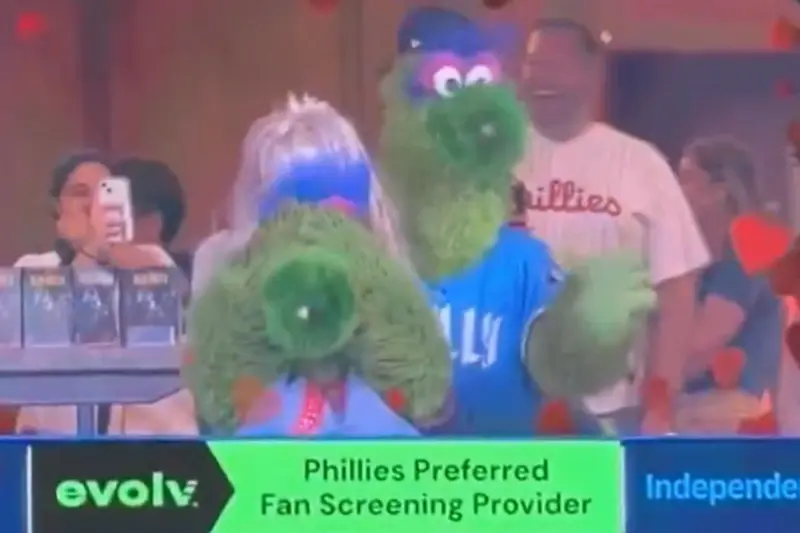 ▲城費城人隊在美國時間週五對戰天使隊的比賽中，球場上演一場別開生面的娛樂橋段，讓全場觀眾笑聲不斷。知名吉祥物「費納寶」（Phillie Phanatic）與另一位戴金色假髮的吉祥物，在場中重現近日爆紅的Coldplay演唱會「偷情Kiss Cam」畫面。（圖／翻攝自YouTube）