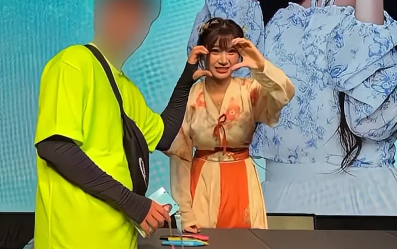 ▲李珠珢（右）與男粉絲比愛心合照時，露出皺眉怪表情，一度被質疑是嫌棄粉絲，但真相並非如此。（圖／翻攝自내맘찍영YouTube）