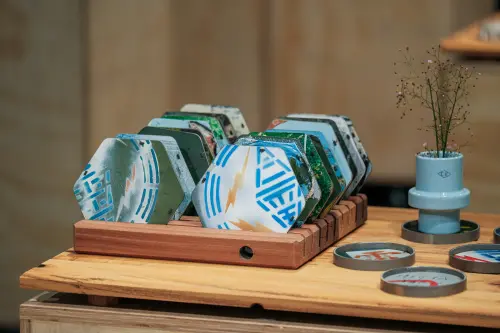 ▲台電說明，歷時近2年動員全台區處共同收集近4000片從變電箱拆卸下來的門板，經由設計師重新解構裁切製成餐桌隔熱墊，每片都有專屬的出生地和繪圖。（圖／台電提供）