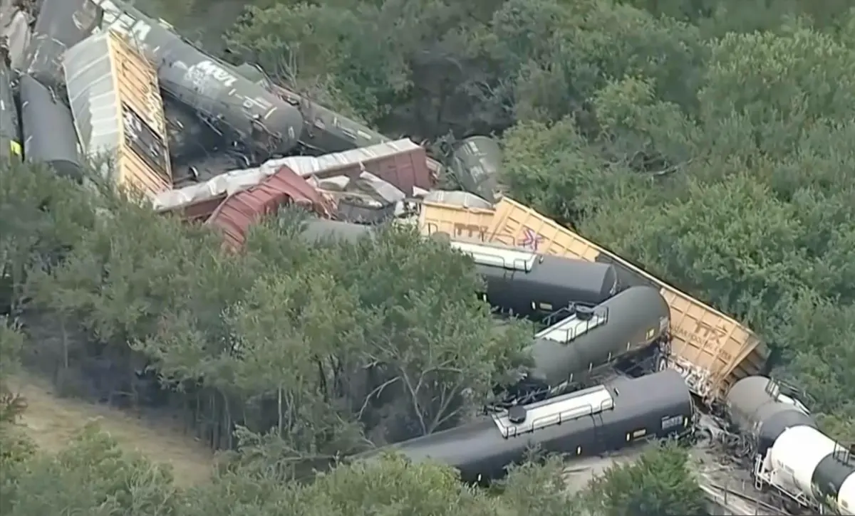 ▲美國德州當地時間12日下午發生一起大規模火車脫軌事故，共有35節車廂脫軌，脫軌現場附近的田野還起火冒出濃煙。（圖／翻攝自美聯社＠WFAA影片）