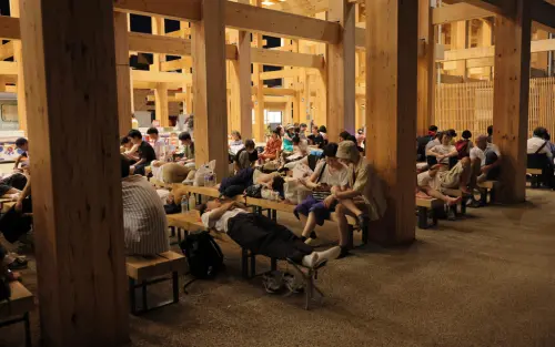 ▲被困在大阪世博會場的遊客只能躺在長椅上睡覺，或是在大屋頂環下的長椅休息。（圖／美聯社／達志影像）