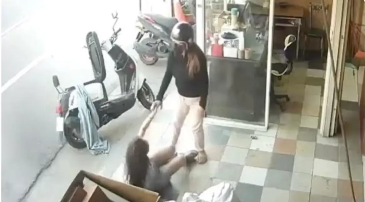 ▲ 黑衣女子在後車廂翻找出磚頭，突然抓住老闆娘頭髮，拿磚頭砸往對方頭部，老闆娘被摔倒在地，兩人在地上扭打。（圖／翻攝畫面）