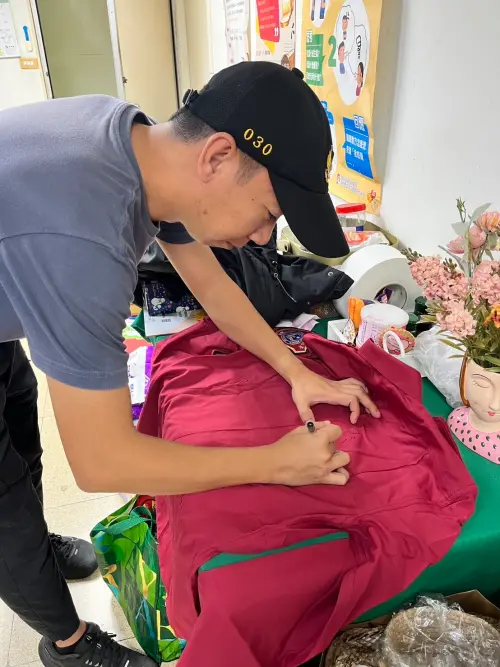 ▲柏源帶著消防員受訓時穿過的紅色制，簽上自己的姓名，親手送給輔導員。（圖／高市府少年隊提供）