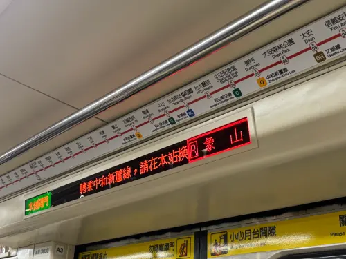 ▲實際觀察台北捷運紅線，到站時兩端會固定「本側開門」、「(R)象山（終點站）」資訊，中間則是跑一堆轉乘資訊或警語，卻時無法到站抬頭就知道現在在哪站。（圖／記者徐銘穗攝）
