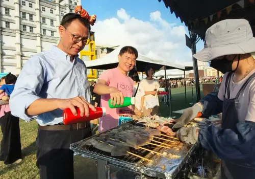 ▲高雄市政府海洋局舉辦2025高雄魷魚季活動，高雄市政府副秘書長王宏榮(左)與海洋局局長石慶豐(右)和民眾一同烤魷魚同樂。(圖／高雄市政府海洋局提供)