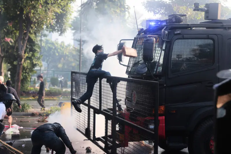 ▲印尼示威者攻擊警方鎮暴車輛，現場煙霧瀰漫情勢緊張。示威群眾試圖破壞執法裝備，警民衝突持續升溫。（圖／美聯社／達志影像）