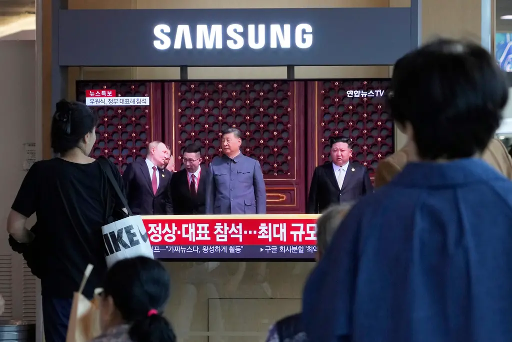 ▲中國3日舉行九三閱兵，韓國首爾火車站的新聞節目播出習近平、蒲亭、金正恩同台的畫面。（圖／美聯社／達志影像）