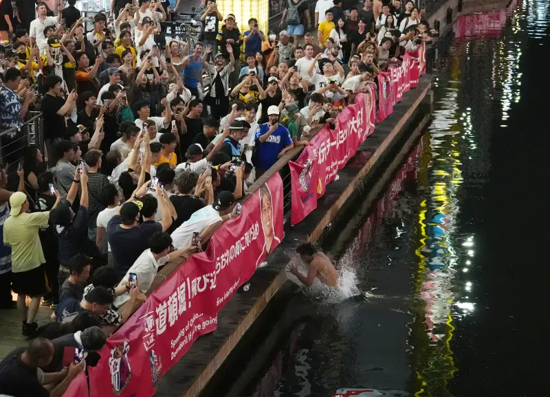 ▲日本職棒中央聯盟人氣球隊阪神虎隊昨日擊敗廣島鯉魚隊，達成中央聯盟史上最快封王紀錄，許多球迷紛紛跳入道頓堀川慶祝。（圖／美聯社／達志影像）