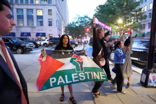 ▲抗議者在餐廳外繼續舉著巴勒斯坦與加薩的旗幟抗議。（圖／美聯社／達志影像）