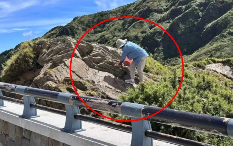 ▲合歡山一名藍衣大媽竟為拍風景照翻越欄杆、攀上岩石，畫面被網友拍下PO網，引發討論。(圖／翻攝爆料公社)
