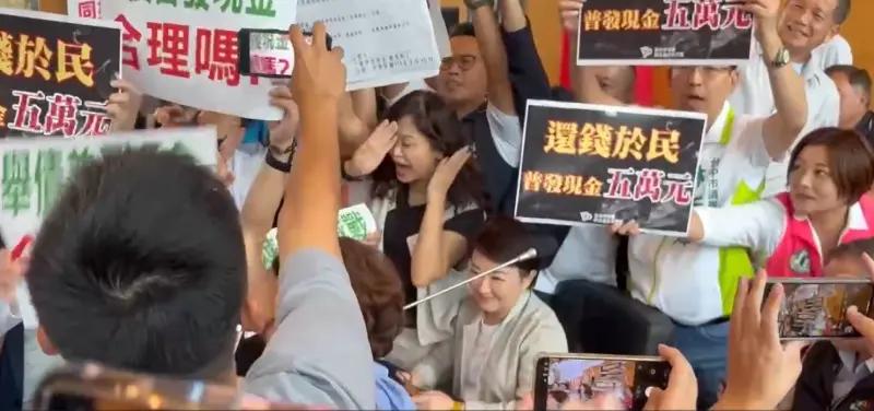 ▲藍綠議員各自舉牌攻佔議事台，坐在備詢席的盧秀燕被淹沒在人海中，笑看亂象。（圖／記者顏幸如攝，2025.09.15）