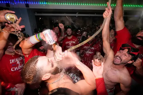 ▲封王後，費城人全隊開心慶祝，強打哈波（Bryce Harper）赤裸上身接受酒水洗禮。（圖／美聯社／達志影像）