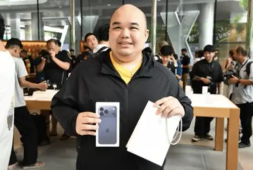 ▲泰國首位買到 iPhone 17 的顧客 Ping 開心展示新機，現場引來媒體與其他果粉圍觀拍照。（圖／翻攝自泰國頭條新聞）