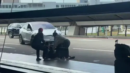 ▲坐在白色特斯拉的乘客被急甩出車外，腿部受傷，旁人急忙攙扶。（圖／翻攝畫面）