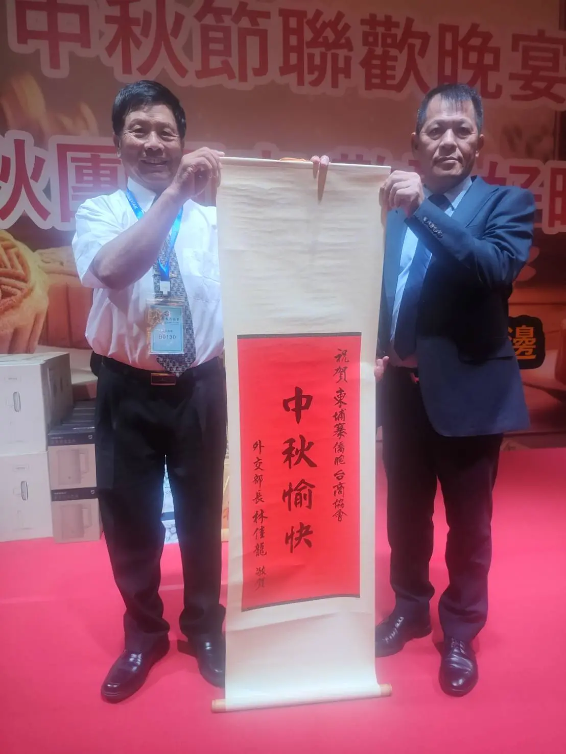 ▲柬埔寨台商提前於20日晚間在金邊明飯店舉辦中秋晚會，僑務委員張清商會長(左），與台商會長陳來埤展示外交部長林佳龍致贈祝賀匾額。（圖／台商會提供）