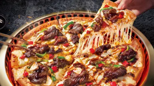 ▲達美樂中秋節聯名胡同燒肉「秘醬嫩牛燒肉披薩」外帶半價優惠469元開吃。必勝客聯名台中屋馬燒肉，肉量升級40%「月見七盎司厚燒牛披薩」半價459元，回歸199元「月亮圈圈」。（圖／達美樂提供）