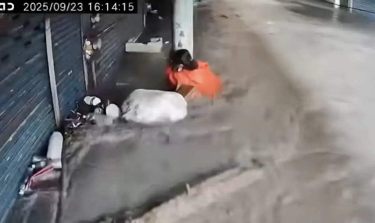 ▲為避免被水流沖走，一名婦人緊抱著電線桿。（圖／民眾提供）