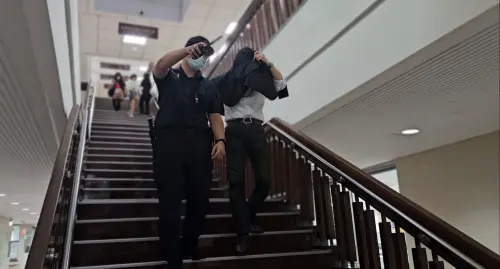 ▲薛楷莉邱姓前男友開庭結束為避免媒體拍到臉，以外套矇頭行走，由法警指引出路，卻因為根本看不清楚而撞到金屬探測門。（圖／記者劉松霖攝）