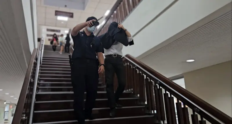    ▲薛楷莉邱姓前男友開庭結束為避免媒體拍到臉，以外套矇頭行走，由法警指引出路，卻因為根本看不清楚而撞到金屬探測門。（圖／記者劉松霖攝）  