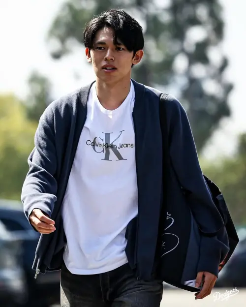 ▲佐佐木朗希身穿CALVIN KLEIN的白T與深藍毛衣、搭配牛仔褲，造型簡約又俐落。但吸引眾人目光的，卻是他的包包——那是千葉羅德海洋隊的官方商品，包上印著前隊友高野脩汰的臉與簽名。（圖／翻攝自洛杉磯道奇IG）