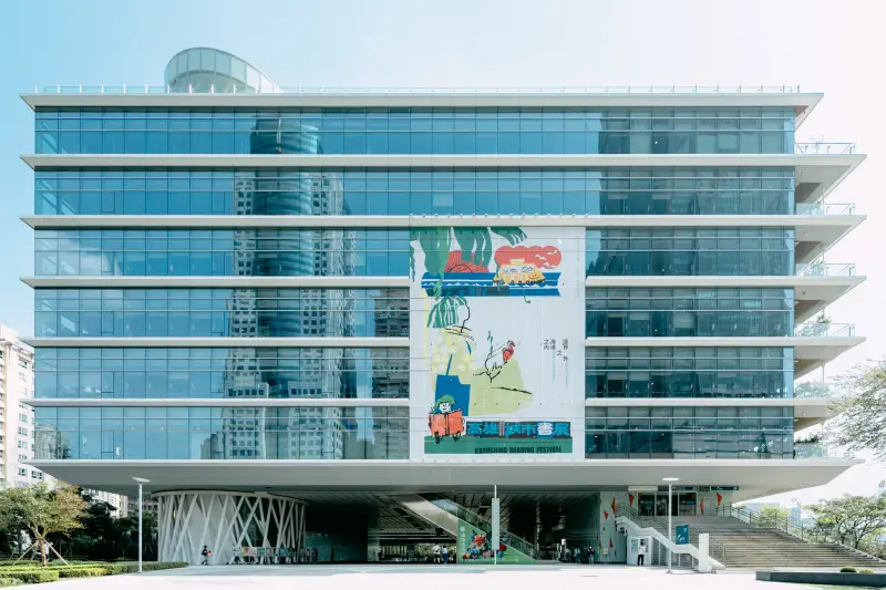 ▲由插畫家林小杯繪製、設計師吳睿哲操刀設計的主視覺，懸掛於高市圖總館外牆，宣告2025高雄城市書展即將盛大登場。(圖／高市府提供)