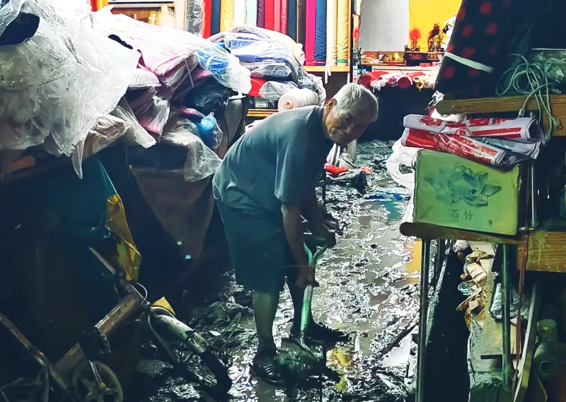 A Guangfu shop owner shovels mud. (TCN photo)