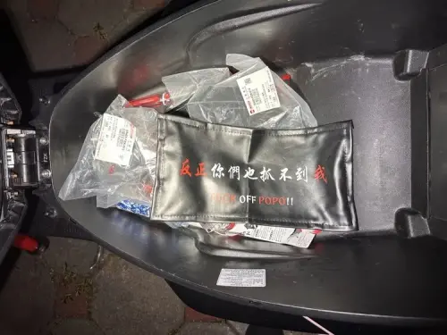 ▲台中女深夜騎改裝車炸街遭警方攔查，員警發現其車車廂內有一塊印著「反正你們也抓不到我 」、「FXXK OFF POPO!!」字樣的車牌套。（圖／民眾提供）