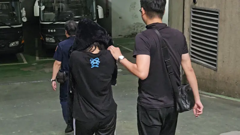 ▲黃牛集團首腦張依萍二度落網,因為用外套蓋頭看不清路,移送時一度走向囚車。(圖/記者劉松霖攝)