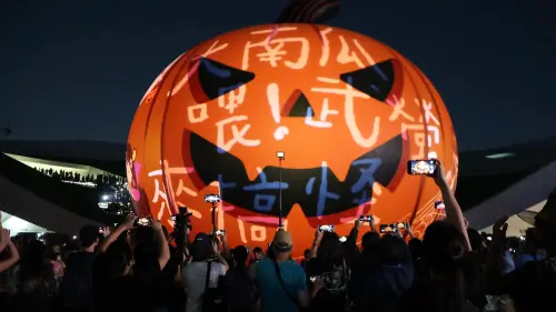 ▲22公尺巨型南瓜燈光秀在衛武營戶外廣場正式啟動，吸引民眾舉起手機拍下巨型南瓜在夜空閃耀的絢爛畫面。（圖／高市府教育局提供）