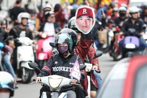 ▲有不少樂天桃猿球迷舉著球員看牌，全程跟著封王遊行隊伍。（圖／記者朱永強攝，2025.11.2）