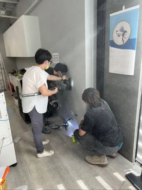 ▲方英傑與現場員工再度研判位置，決定鋸開辦公室內部牆面。（圖／新北市動保處）