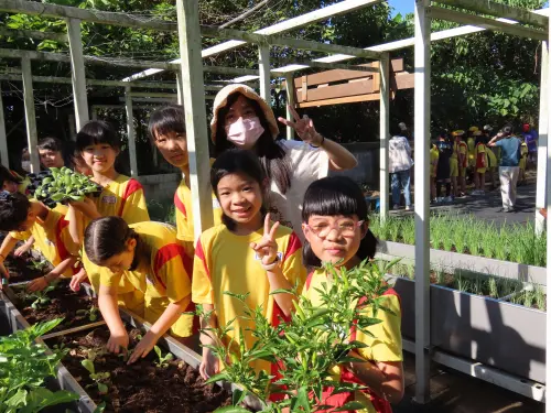 ▲學生代表將花籽輕灑入土，寓意希望的種子在大地中生根發芽。