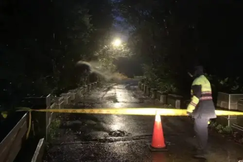 ▲新北瑞芳的山尖路石山橋也受到鳳凰颱風外回環流影響，山壁坍方、土石滑落路面，警方到場設置封鎖線警戒。（圖／翻攝畫面）