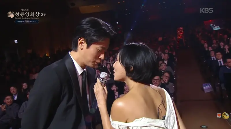 ▲華莎（右）赤腳登青龍獎表演，朴正民（左）站在台下拿著紅色高跟鞋紳士等候，不料鞋子直接被華莎丟掉，讓他著急狂喊：「把高跟鞋拿走」。（圖／KBS Entertain YouTube）