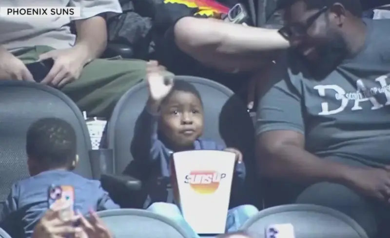 ▲年僅3歲的小球迷史特林（Sterling）在太陽隊比賽中因抱著巨大桶子狂吃爆米花而爆紅，被網友暱稱為「爆米花小子」。他發現自己登上大螢幕後的可愛反應，在網路上累積超過5000萬次點閱。（圖／翻攝自社群媒體X，KHOU 11）