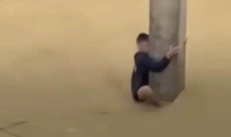 ▲一名男子因突遇暴漲洪流，被迫攀上細長混凝土柱避難並緊抱鋼筋達七小時才被救。（圖／翻攝自影片）