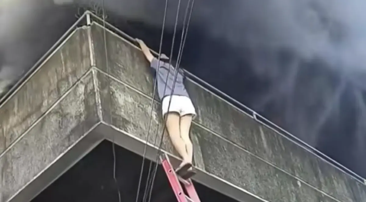 ▲菲律賓宿霧一棟工業大樓發生火警，一名女子在濃煙中先救出2隻狗，再循消防梯安全脫困，畫面在網路上引發熱議。（圖／翻攝自Manila Bulletin）