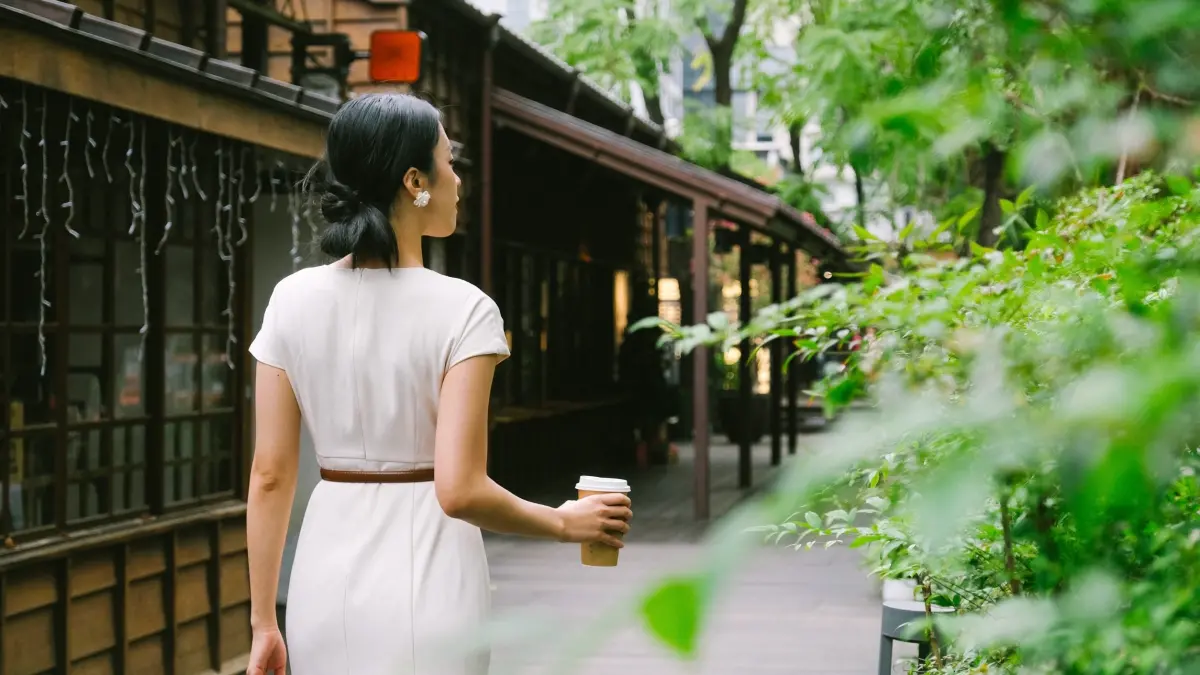 ▲午後的榕錦時光生活園區，旅人手捧咖啡行走於木造廊道間，老屋與綠蔭交織，咖啡香在光影中流動。（圖／翻攝畫面）