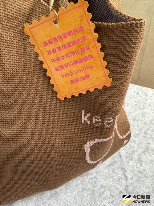 ▲林光寧追思會回禮的提袋，印有粉紅色的眼鏡圖案以及「Keep smiling」（保持微笑）字樣，隨袋附上的橘色小吊牌，揭示了每樣禮物的特殊含義，家屬代替林光寧送給大家最後的祝福與叮嚀，希望親友們帶著這份心意，繼續快樂順遂地生活。（圖／記者李欣恬攝影）