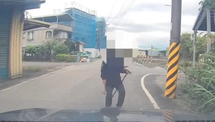 ▲ 宜蘭蔡姓男子右手拿斧頭、左手持拐杖，對著來往人車揮舞。（圖／翻攝畫面）