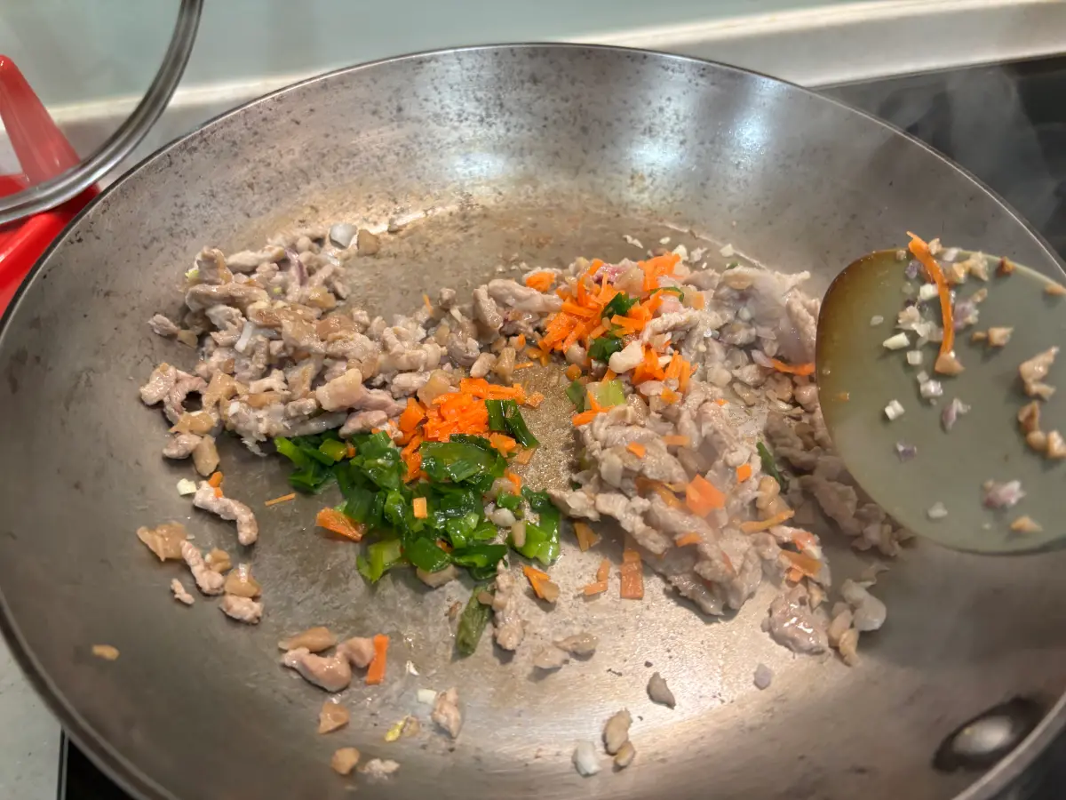 肉絲出油後，加入蒜碎、蔥花、紅蘿蔔絲炒香（若油量不足可補少許食用油）