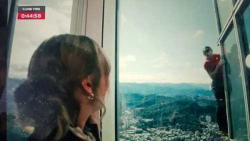 ▲霍諾德攀爬到第44分鐘時，妻子桑妮（Sanni McCandless）突然出現在台北101大樓內部替丈夫加油。（圖／翻攝自Netflix）
